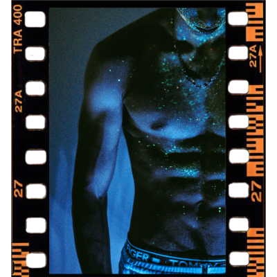Film strip image containing an image of a shirtless man covered in blacklit glitter